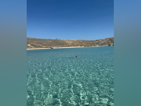 A swimmer enjoys the crystal-clear waters of a beautiful beach, perfect for snorkeling and relaxation under the sun.