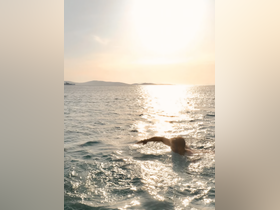 A swimmer enjoys the serene ocean waters during sunset, capturing the essence of a perfect day on the water.