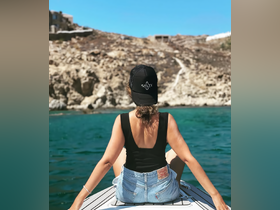 A woman enjoys the serene view from the back of a boat, overlooking a stunning coastline — a perfect moment of relaxation on the water.