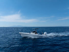 A sleek speedboat glides through the clear blue waters, showcasing its design and performance under a bright sky.