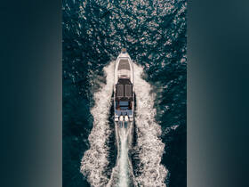 Aerial view of a sleek speedboat cruising through sparkling waters, showcasing its modern design and solar panels — perfect for eco-friendly boating adventures.
