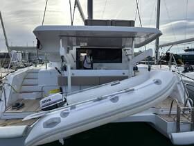 A sleek catamaran docked at the marina, showcasing its spacious deck and tender. Ideal for luxury charters and sailing adventures.