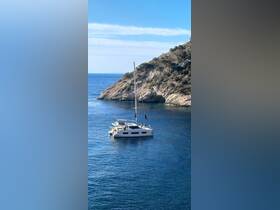 A stunning aerial view of a catamaran sailing in clear blue waters, surrounded by rocky cliffs — perfect for exploring coastal destinations.