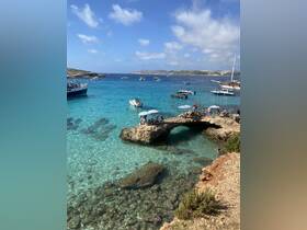 A vibrant scene at a popular beach with groups enjoying the clear turquoise waters, surrounded by boats and rocky formations — perfect for summer fun and relaxation.