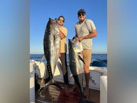Two anglers proudly display their impressive catch of tuna while enjoying a successful fishing trip at sea — a perfect moment for fishing enthusiasts.
