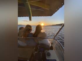 A group of friends enjoys a stunning sunset from the deck of a boat, creating a perfect backdrop for memorable moments on the water.