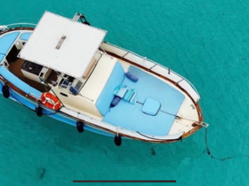 Aerial view of a beautifully designed boat anchored in crystal-clear waters, showcasing its spacious deck and inviting seating area.