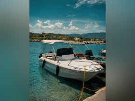 A sleek speedboat docked in clear turquoise waters, surrounded by a picturesque harbor and lush hills — perfect for a day of exploration on the water.