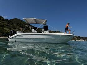 A young boy enjoys a fun moment on the bow of a boat, showcasing the excitement of water activities in a beautiful setting.
