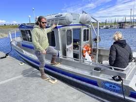 A man and a woman enjoy a moment on a boat at the dock, showcasing the perfect setting for a day on the water.