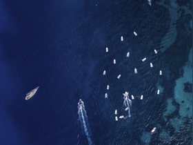 A stunning aerial view of multiple boats navigating through deep blue waters, showcasing the vibrant boating activity in the area.