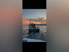 A group of fishermen aboard the 'Big Dog' boat enjoy a picturesque sunset while fishing, capturing the essence of a perfect day on the water.