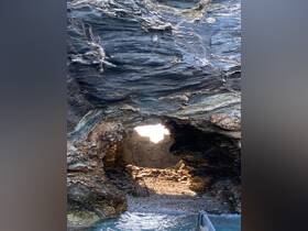 A stunning view of a natural cave opening, revealing a sunlit interior and rocky shoreline — a perfect destination for exploration and adventure on the water.