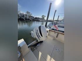 A detailed view of a boat's outboard motor docked at the marina, showcasing the serene waterfront and nearby vessels.