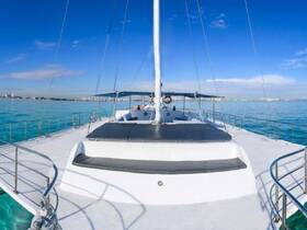 A stunning view of a catamaran sailing through crystal-clear waters, showcasing its sleek design and inviting deck space — perfect for leisurely cruises.