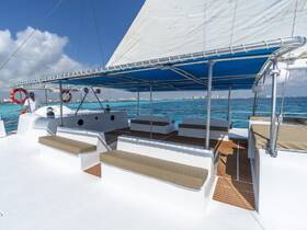 The interior of a spacious catamaran features comfortable seating and a helm, perfect for relaxing while cruising the turquoise waters.