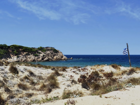 A picturesque view of a serene beach with rocky cliffs and clear blue waters, perfect for a relaxing getaway or island exploration.
