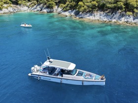 An aerial view of a boat anchored in crystal-clear waters, with guests enjoying the serene coastline — a perfect setting for a day of relaxation and exploration.
