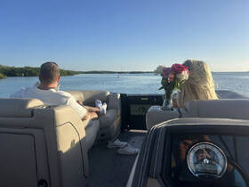A couple enjoys a serene moment on a boat, surrounded by beautiful scenery and fresh flowers, perfect for a romantic getaway.