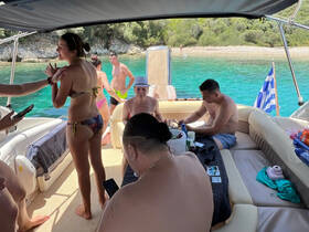 A lively group enjoys a fun day on the boat, engaging in conversation and relaxation under the sun, surrounded by beautiful turquoise waters.