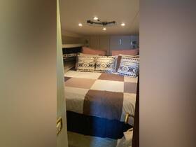 Cozy cabin interior featuring a comfortable bed adorned with decorative pillows, perfect for relaxing on a boat getaway.