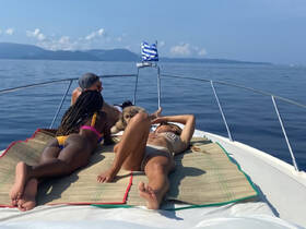 A group of friends relaxes on the bow of a boat, enjoying the sun and beautiful ocean views — perfect for a day of leisure on the water.