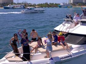 A lively group waves from the deck of a yacht, enjoying a fun day on the water — perfect for celebrations and memorable outings.