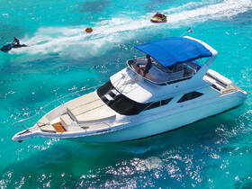 An aerial view of a yacht cruising through crystal-clear waters, with thrilling jet ski and tubing activities in the background — perfect for adventure seekers enjoying a day on the water.
