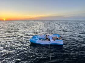 Two friends relax on a floating mat as the sun sets over the water, creating a perfect backdrop for a summer getaway.