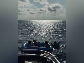 A group of friends enjoys a sunny day on the water, relaxing on floating mats while the boat is anchored nearby — a perfect scene for summer fun and relaxation.