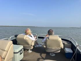 A couple enjoys a serene moment on a boat, taking in the beautiful scenery and tranquil waters — perfect for a relaxing day on the water.