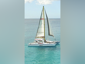 A vibrant catamaran named 'SHASA II' sails through clear turquoise waters, showcasing the beauty of sailing adventures.