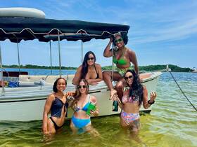 A lively group of friends enjoys a sunny day in the water, celebrating with drinks and laughter beside their boat — perfect for summer outings and memorable adventures.