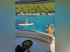 A vibrant scene of two friends enjoying a sunny day on the water, with one paddleboarding and the other capturing the moment on camera — perfect for summer adventures and water activities.