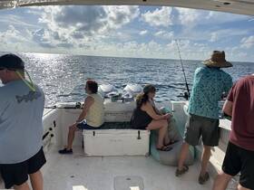 A group of friends enjoys a fishing trip on a boat, casting lines into the sparkling ocean under a beautiful sky — perfect for adventure seekers and fishing enthusiasts.