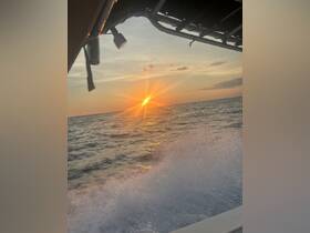 A stunning sunset view from the side of a boat, capturing the vibrant colors reflecting on the ocean's surface — perfect for serene evening cruises.