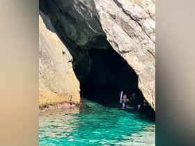 A family enjoys snorkeling in a stunning cave with crystal-clear waters, creating unforgettable memories in a picturesque setting.