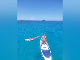 A couple enjoys a sunny day paddleboarding and swimming in crystal-clear turquoise waters, perfect for adventure seekers and water lovers.