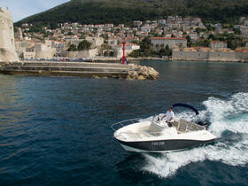 A motorboat navigates through clear waters near a picturesque coastline, showcasing the beauty of the surrounding landscape.