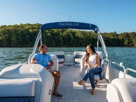 A cheerful couple enjoys a relaxing moment on a boat, surrounded by serene lake views — perfect for a day of leisure on the water.