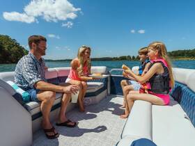 A joyful family enjoys snacks on a pontoon boat under the sun, creating perfect memories on the lake.