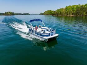 A couple enjoys a scenic ride on a pontoon boat, gliding through calm lake waters surrounded by lush greenery — perfect for a relaxing day on the water.