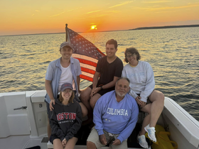 A joyful family poses on a boat at sunset, capturing a memorable moment together on the water — perfect for family gatherings and celebrations.