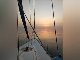 A serene sunset view from the bow of a sailboat, showcasing calm waters and a beautiful horizon — perfect for tranquil sailing experiences.