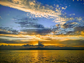 A breathtaking sunset over calm waters, showcasing vibrant colors and dramatic clouds — a perfect backdrop for evening boat cruises.