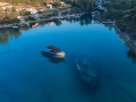 An aerial view of a boat navigating through clear waters, showcasing the serene landscape and a submerged vessel in the background, perfect for exploring coastal beauty.