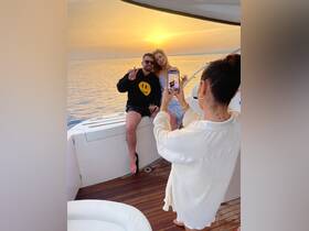 A couple enjoys a picturesque sunset on a yacht, capturing the moment with a photo — perfect for romantic getaways and memorable celebrations on the water.