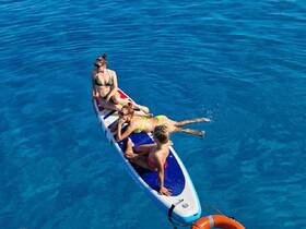 A group of friends enjoys a sunny day paddleboarding in crystal-clear waters, perfect for summer adventures and aquatic fun.