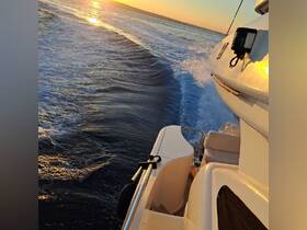 A stunning view of a yacht cruising through the water at sunset, showcasing the vessel's sleek design and the beautiful golden reflections on the waves.