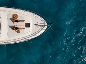Two women relax and sunbathe on the deck of a luxury boat, surrounded by stunning turquoise waters — an ideal scene for a summer getaway or yacht charter experience.